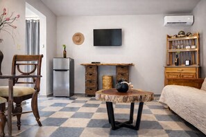 A compact living space with a dining table, a sofa, a TV, a refrigerator, and a bookshelf. - Bremar Collection Boutique Hotel (Celestún)