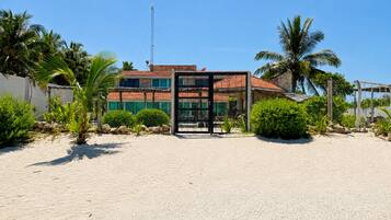 A beachfront property with a gated entrance, a building with a red-tiled roof, and palm trees.