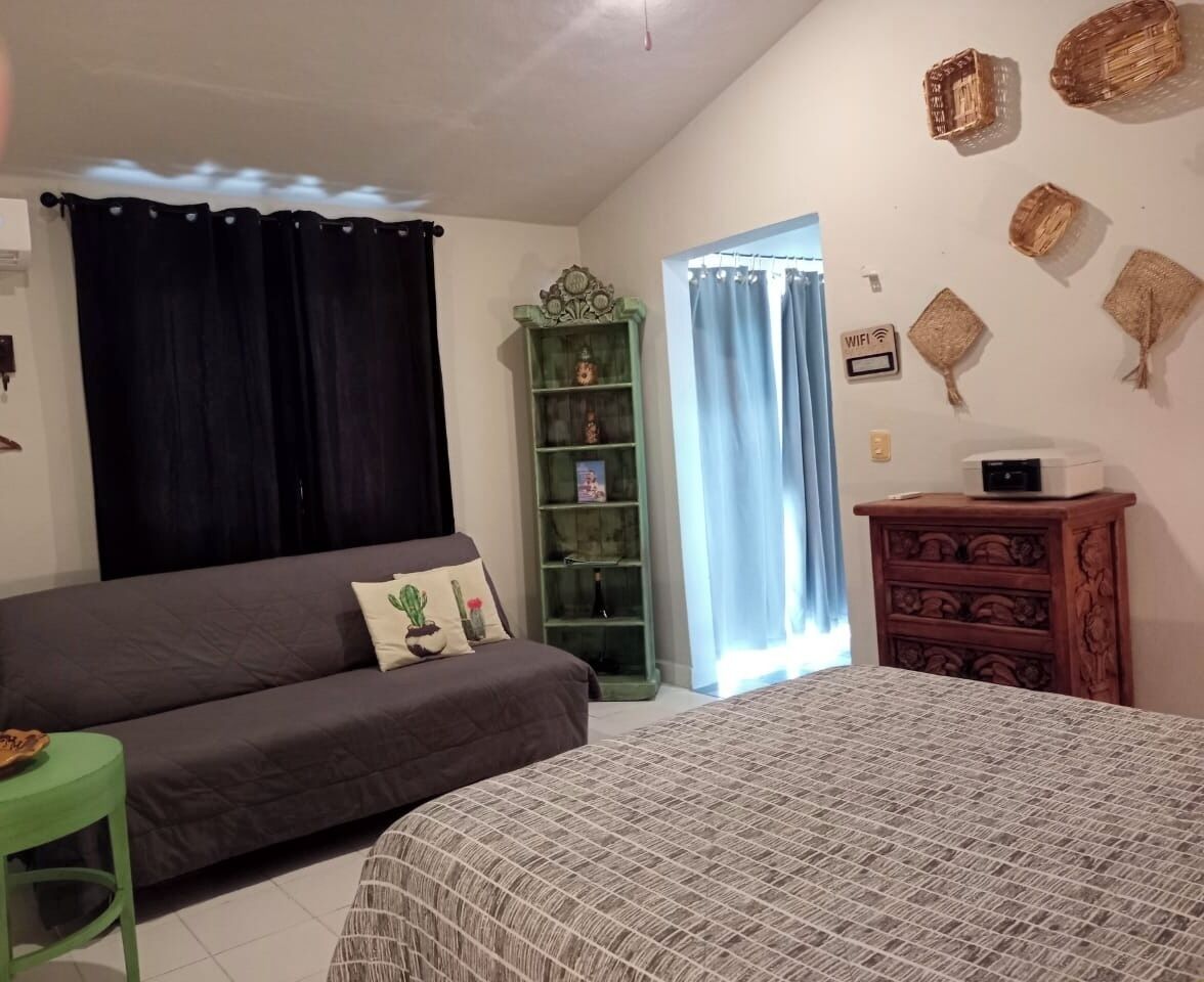 Un dormitorio con cama, una silla verde, una estantería y un aparador.