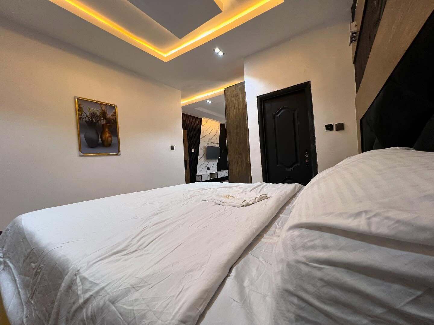 Een hotelkamer met een groot bed, een schilderij aan de muur en een modern plafondontwerp.