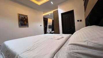 Een hotelkamer met een groot bed, een schilderij aan de muur en een modern plafondontwerp.