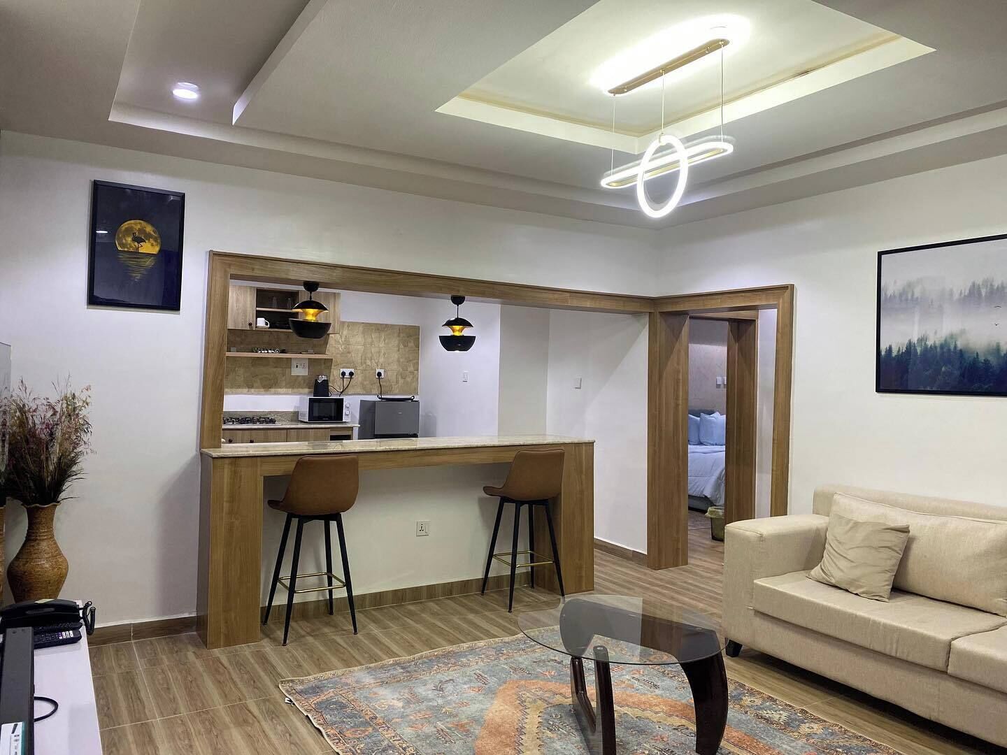 A modern living room with a kitchen area, a glass coffee table, and a sofa.
