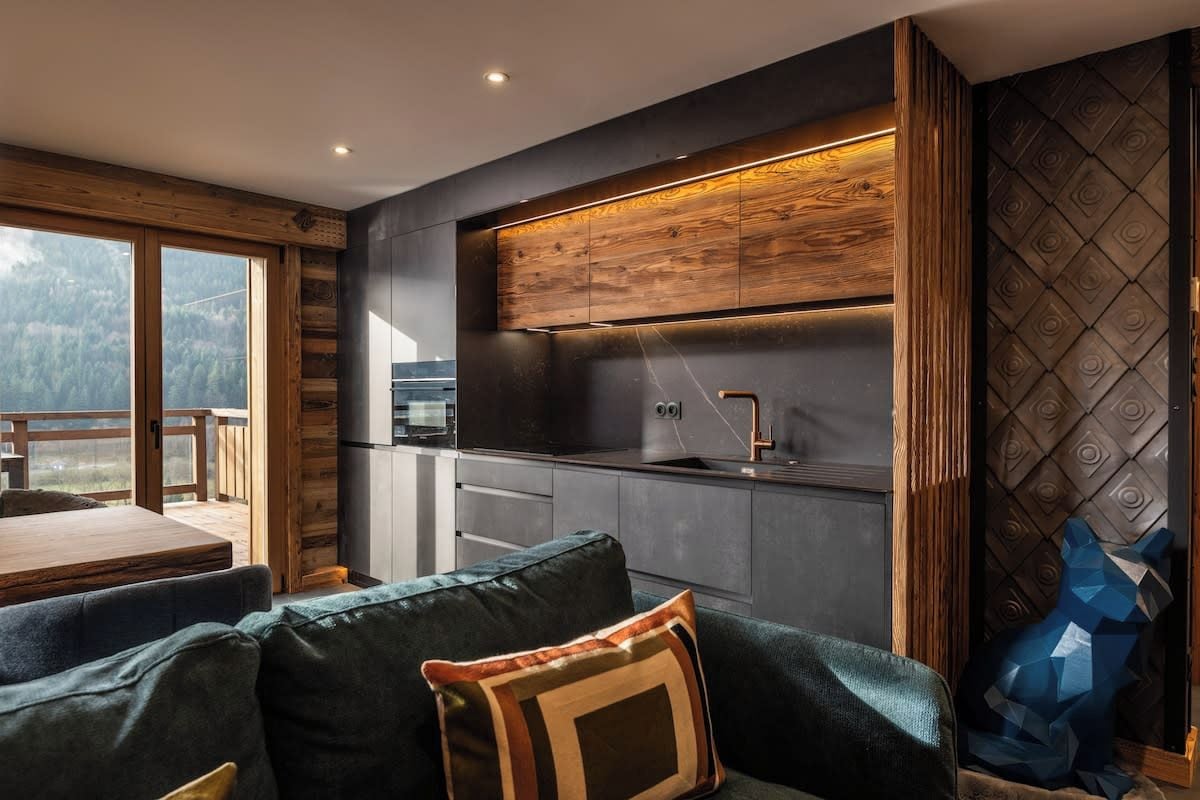 A modern kitchen with a wooden accent wall, a built-in oven, and a sink.
