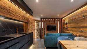 A modern kitchen with a black countertop and wooden wall paneling. - Chalet Le Mirador - Sauna - Hammam (Ventron)