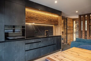 Une cuisine moderne dotée d’un four encastré, d’un évier et d’un mur d’accent en bois.