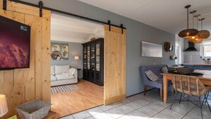 A spacious living area with a sliding wooden door leading to a dining space, a sofa, and a cabinet with glass doors.