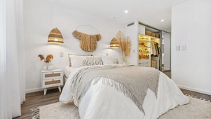 Un dormitorio moderno con una cama grande, mesitas de noche, un armario y adornos en la pared.