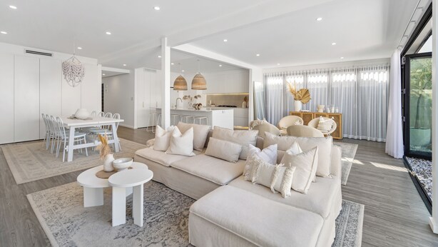 Una sala de estar moderna con un sofá modular, comedor y cocina.