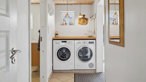 A laundry room with two washing machines, a wooden ceiling, and a mirror on the wall. - Cozy holiday home in Harboøre (Harboøre)