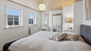 A bedroom with a large bed, wooden ceiling, and a window with a view. - Cozy holiday home in Harboøre (Harboøre)