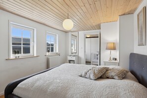 A bedroom with a large bed, wooden ceiling, and a window with a view.