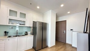 Una cocina moderna con armarios blancos, un refrigerador de acero inoxidable y suelo de madera.