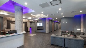 A modern lobby with a reception desk, seating area, and a large pillar.