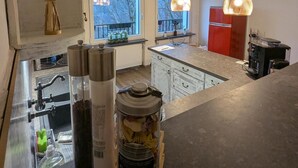 A modern kitchen with a central island, pendant lights, and a view of the outdoors.