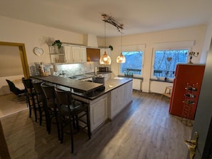 A modern kitchen with a central island, bar stools, pendant lighting, and a view of the outdoors. - Apartment 'Am Steinweg' with Mountain View, Private Terrace and Wi-Fi (Solingen)