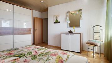 Een slaapkamer met een bed, een kledingkast, een bureau, een stoel en een spiegel.