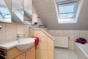 Une salle de bain moderne avec un puits de lumière, un lavabo, un miroir et un porte-serviettes.