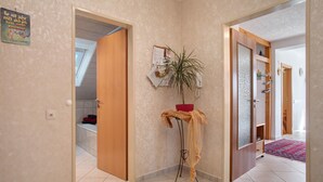 A hallway with a wooden door, a small table with a plant, and a red bowl. - Apartment 'Plocher' with Lake View, Shared Garden and Wi-Fi (Immenstaad am Bodensee)