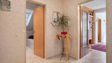 A hallway with a wooden door, a small table with a plant, and a red bowl.