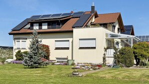 A two-story house with solar panels, a conservatory, and a well-maintained garden. - Apartment 'Plocher' with Lake View, Shared Garden and Wi-Fi (Immenstaad am Bodensee)