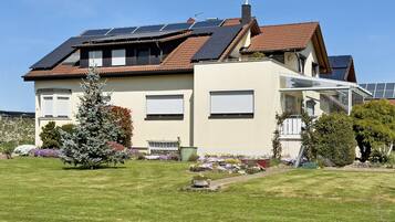 A two-story house with solar panels, a conservatory, and a well-maintained garden.