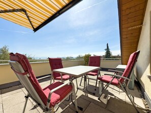 Une terrasse avec une table et des chaises, une vue sur le ciel et une structure en bois.