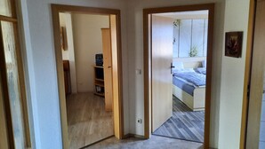 A room with a bed, a wooden wardrobe, and a small hallway leading to another room. - Apartment 'Börner' with Mountain View and Wi-Fi (Frauenstein)