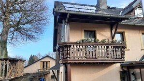 A two-story house with a balcony, a wooden staircase, and a small garden area. - Apartment 'Börner' with Mountain View and Wi-Fi (Frauenstein)