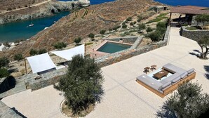 A pool area with a view of the sea, surrounded by stone walls and olive trees. - Villa Mariana by Boutique (Folegandros)