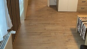 A room with a wooden floor, a white cabinet with drawers, a black flat-screen TV, and a small white radio. - Holiday Apartment 'Braun' with Mountain View and Wi-Fi (Lindau)