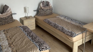 A minimalist room with two beds, a nightstand, a lamp, a zebra painting, and a wall art piece. - Holiday Apartment 'Braun' with Mountain View and Wi-Fi (Lindau)