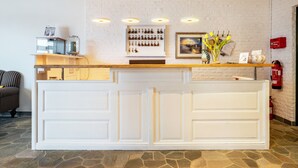A reception desk with a white panel, a framed picture, and a vase with flowers. - Apartment 'Ostseeblick Fewo 6' with Private Terrace, Balcony and Wi-Fi (Kronsgaard)