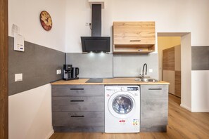 Ett kompakt kök med inbyggd tvättmaskin, kaffebryggare och mikrovågsugn.