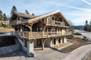 Sturdy chalet-style building with a spacious balcony and large windows.