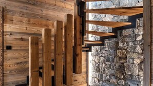 Un interior moderno con vigas de madera, paredes de piedra y suelo de baldosas.