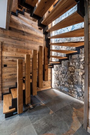 Un interior moderno con vigas de madera, paredes de piedra y suelo de baldosas.