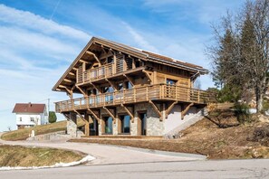 Un chalet en bois doté d’un balcon, avec des fondations en pierre et un ciel dégagé.