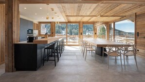 Una cocina moderna con una isla central, vigas de madera y grandes ventanales que ofrecen vistas al exterior.