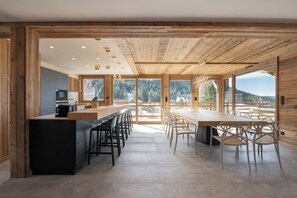 Una cocina moderna con una isla central, vigas de madera y grandes ventanales que ofrecen vistas al exterior.