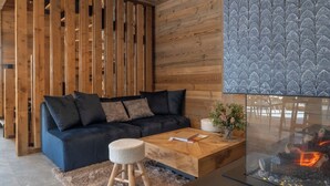 Una sala de estar moderna con un sofá azul oscuro, listones de madera, una mesa de centro de vidrio y una chimenea.