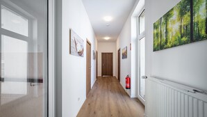 A hallway with wooden flooring, white walls, and framed artwork.