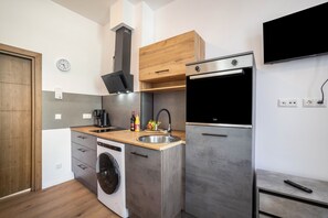 Eine moderne Küche mit eingebauter Waschmaschine, einem Edelstahl-Kühlschrank und einem Holzkorpus.