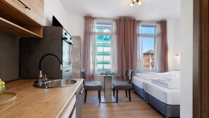 A compact hotel room with a kitchenette, a bed, a small table with chairs, and a window with curtains. - Studio Apartment 3-1 with Wi-Fi (Lübeck)