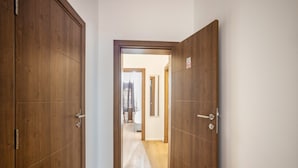 Un pasillo con puertas de madera, un picaporte visible y un interruptor de luz en la pared.