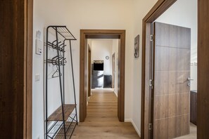 A hallway with a coat rack, wooden flooring, and a door leading to a kitchen area.