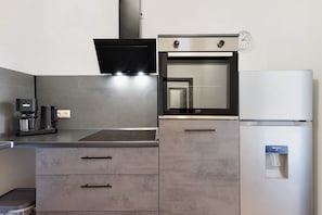 Une cuisine moderne équipée d’un four encastré, d’une machine à café et d’un distributeur d’eau.