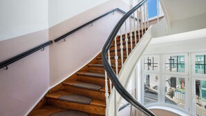 A staircase with wooden steps and a black handrail, leading to a landing with a view of the outside. - 2-bedroom apartment 3-2 with balcony and Wi-Fi (Lübeck)
