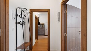 A hallway with a coat rack, wooden flooring, and a door leading to a kitchen area. - 2-bedroom apartment 3-2 with balcony and Wi-Fi (Lübeck)
