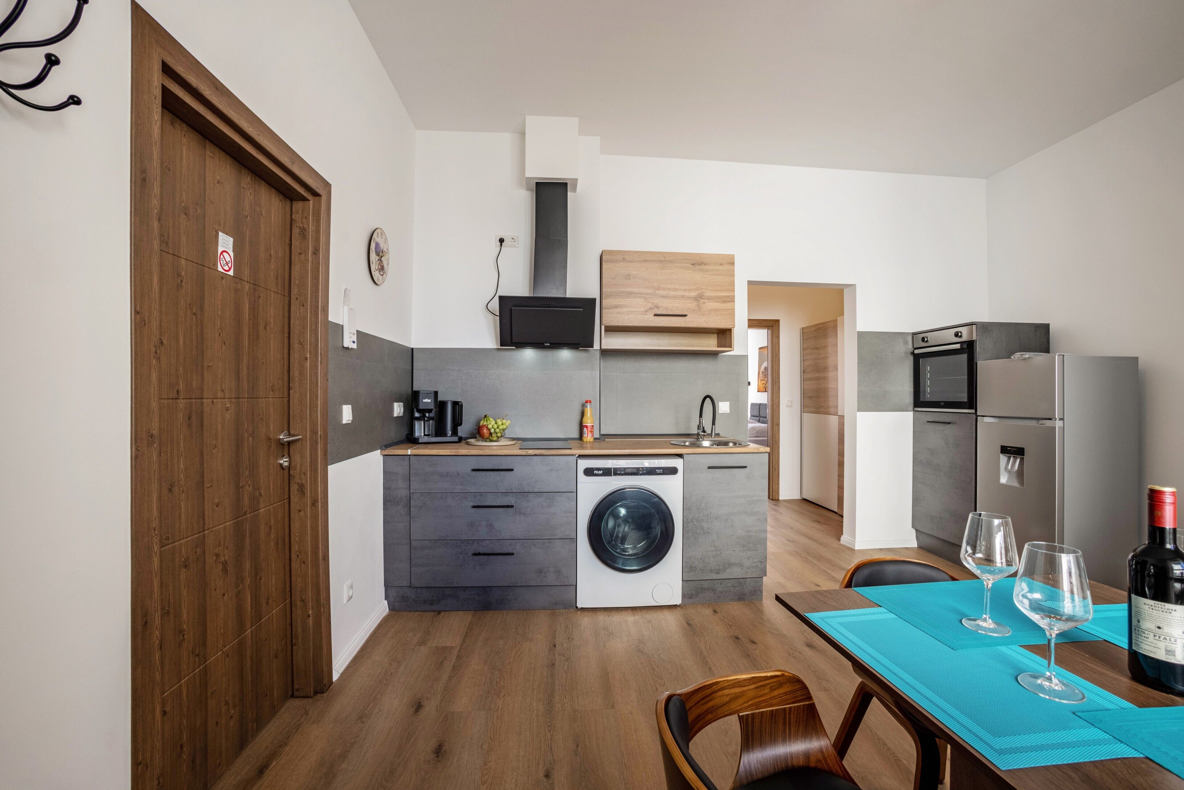 Eine moderne Küche mit integriertem Waschmaschine, einem Essbereich mit Tisch für zwei Personen und einem Kühlschrank.