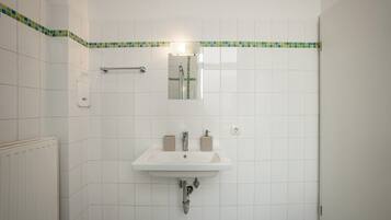 A bathroom with a white sink, mirror, and tiled walls.
